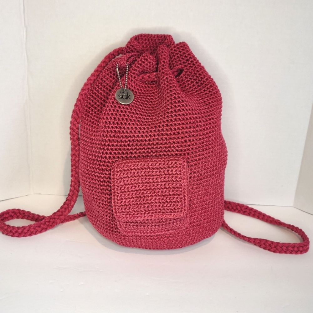 The SAK Backpack Woven Crochet Bucket Style In a pink/burgundy color